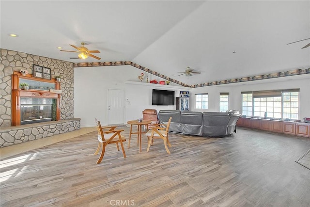 living room featuring vaulted ceiling, a fireplace, wood finished floors, and a ceiling fan