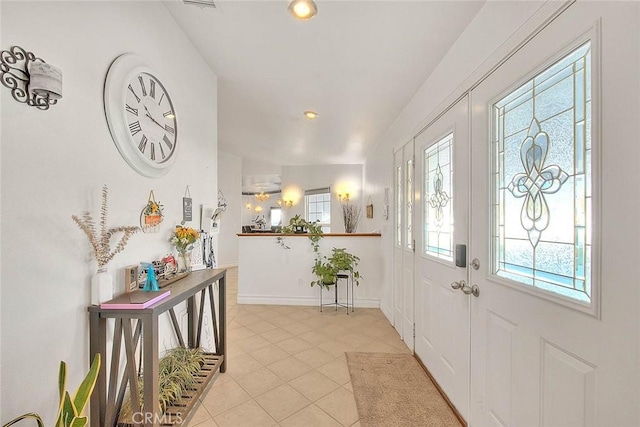 entryway with recessed lighting, a healthy amount of sunlight, baseboards, and light tile patterned floors