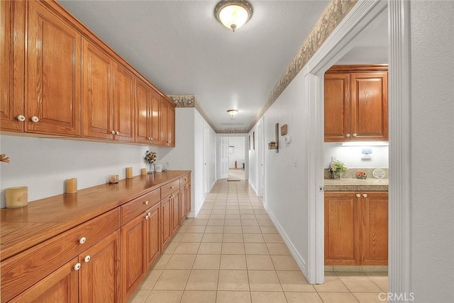 hall featuring baseboards and light tile patterned flooring