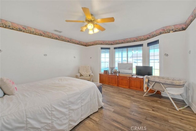 bedroom with a ceiling fan, visible vents, and wood finished floors