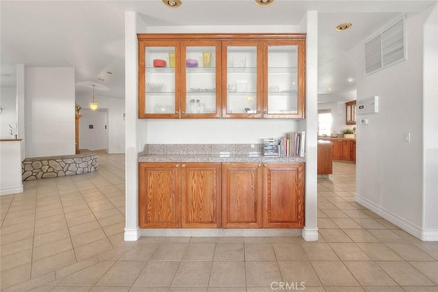 kitchen with light tile patterned floors, baseboards, visible vents, glass insert cabinets, and brown cabinets