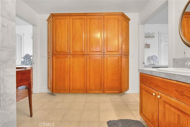 kitchen featuring a sink, light tile patterned floors, brown cabinets, and light countertops