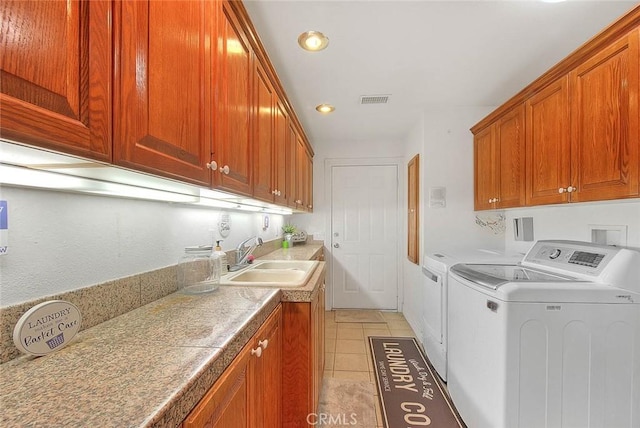 laundry area featuring cabinet space, light tile patterned floors, visible vents, washing machine and clothes dryer, and a sink