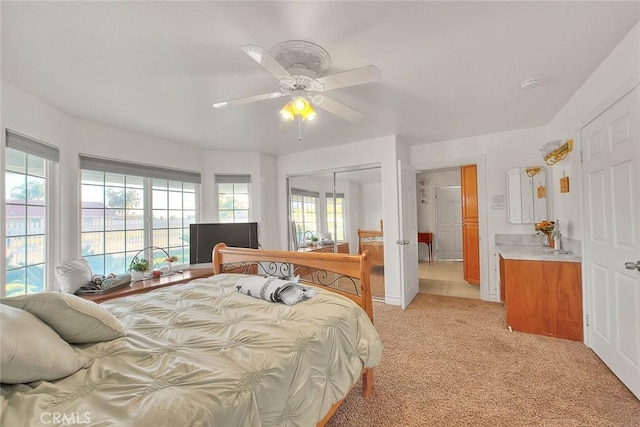 bedroom with a closet, a ceiling fan, and light colored carpet