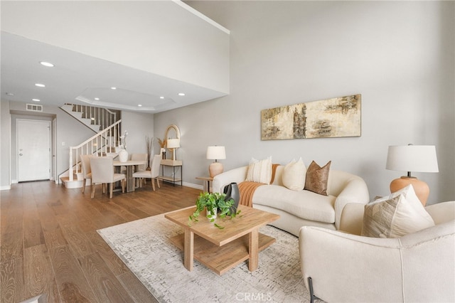 living room with recessed lighting, visible vents, stairway, and wood finished floors