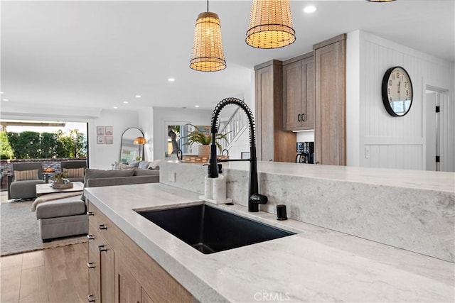 kitchen with recessed lighting, light wood-type flooring, a sink, and light stone countertops