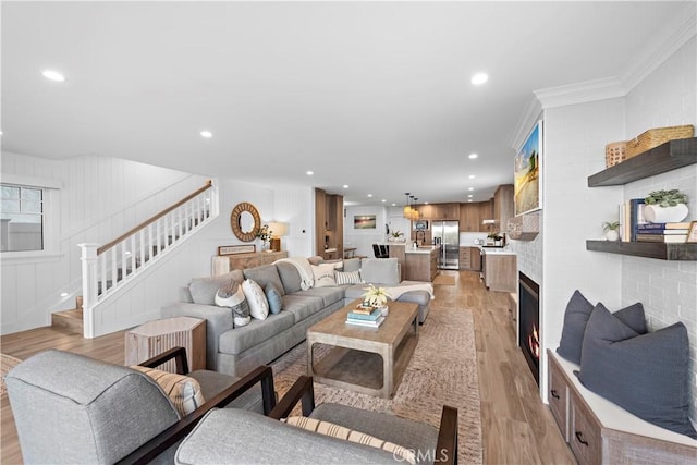 living area with light wood-style floors, stairway, crown molding, and recessed lighting