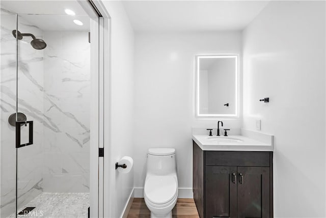 full bath with toilet, wood finished floors, vanity, baseboards, and a marble finish shower