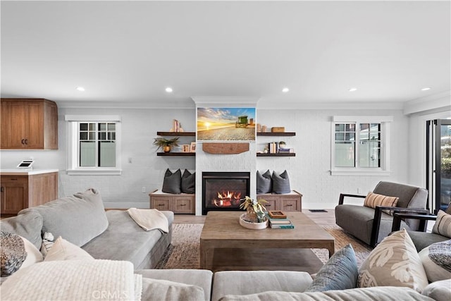 living area featuring light wood-style floors, recessed lighting, a large fireplace, and ornamental molding