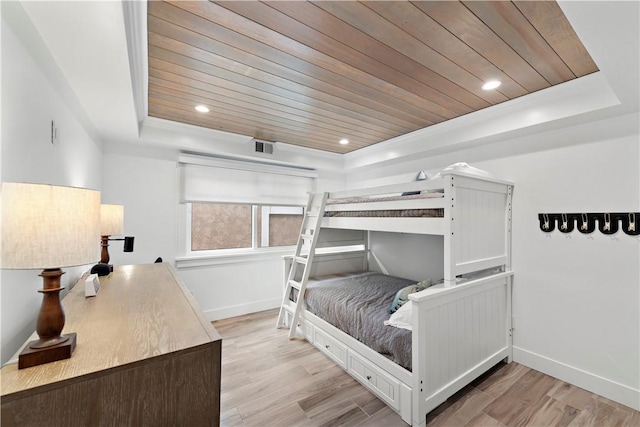 bedroom with baseboards, a raised ceiling, wood ceiling, and light wood-style floors