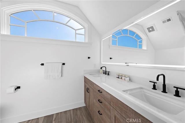 bathroom featuring lofted ceiling, visible vents, a sink, and wood finished floors