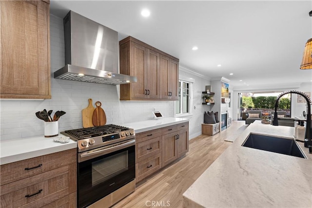 725 Dover Ct, San Diego, CA 92109 - kitchen with a sink, wall chimney range hood, stainless steel gas stove, a fireplace, and light wood-style flooring