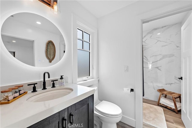 full bathroom with a marble finish shower, toilet, vanity, wood finished floors, and baseboards