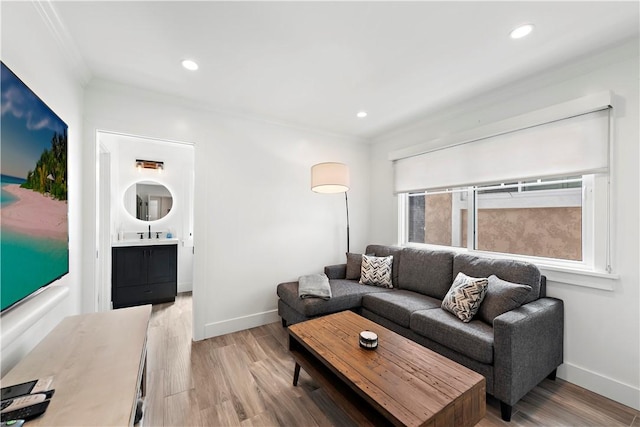 living area with light wood-type flooring, baseboards, crown molding, and recessed lighting