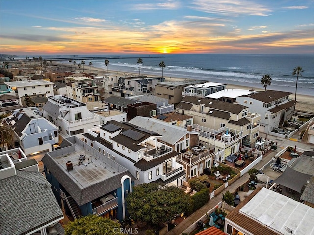 aerial view at dusk featuring a beach view and a water view