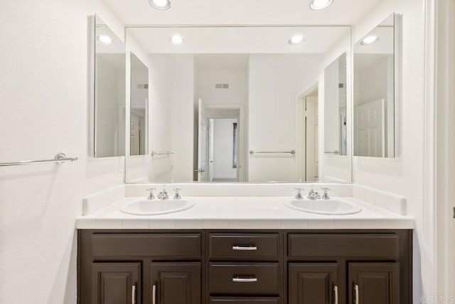 bathroom featuring double vanity, a sink, visible vents, and recessed lighting