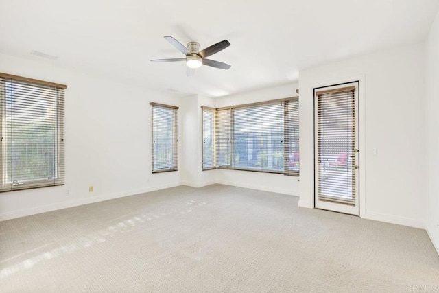 unfurnished room featuring light carpet, plenty of natural light, ceiling fan, and baseboards