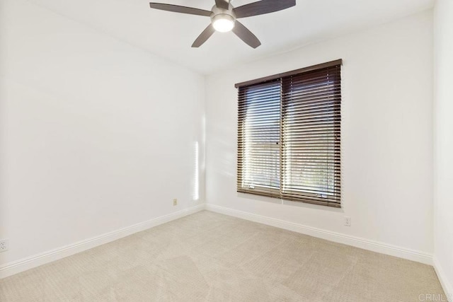 empty room with a ceiling fan, light colored carpet, and baseboards