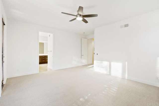 unfurnished bedroom featuring baseboards, visible vents, ensuite bathroom, and light colored carpet