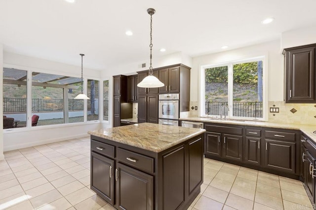 kitchen with stainless steel appliances, backsplash, a sink, dark brown cabinetry, and a kitchen island