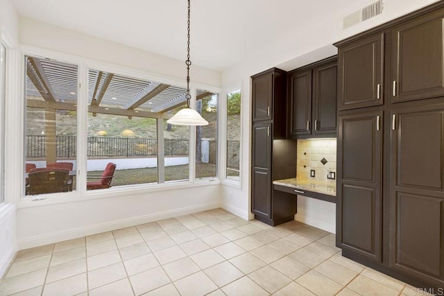 kitchen featuring visible vents, dark brown cabinets, backsplash, built in study area, and decorative light fixtures