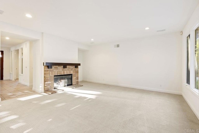 unfurnished living room featuring recessed lighting, baseboards, light colored carpet, and a glass covered fireplace