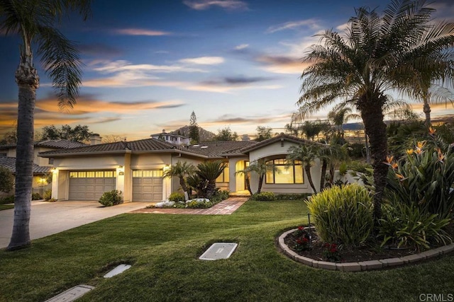 view of front of house with a garage, concrete driveway, a tile roof, a front yard, and stucco siding