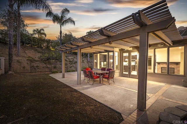 patio terrace at dusk with fence, outdoor dining area, and a pergola