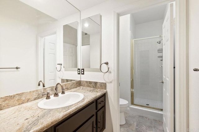 bathroom featuring toilet, a shower stall, and vanity