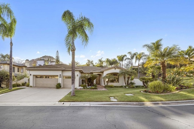 mediterranean / spanish-style house featuring stucco siding, concrete driveway, a front yard, a garage, and a tiled roof