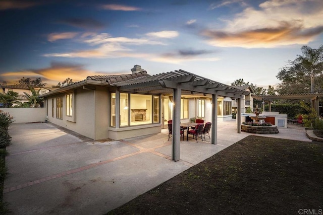 back of property with a tile roof, a chimney, stucco siding, a patio area, and a pergola