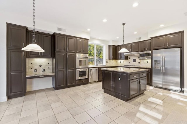 kitchen featuring light stone counters, appliances with stainless steel finishes, light tile patterned flooring, dark brown cabinetry, and under cabinet range hood