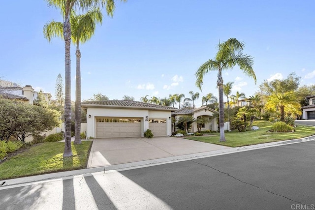 mediterranean / spanish house featuring a garage, driveway, a front yard, and stucco siding