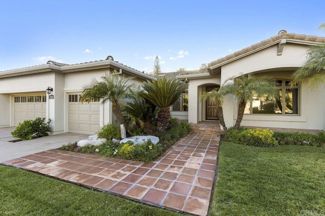 view of front of home with a garage, driveway, a tile roof, and stucco siding