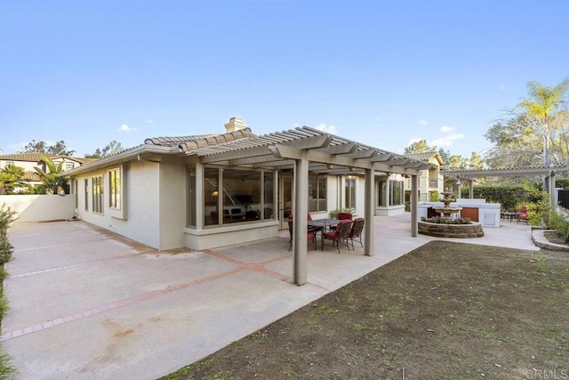 rear view of property featuring stucco siding, a patio area, a chimney, and a pergola