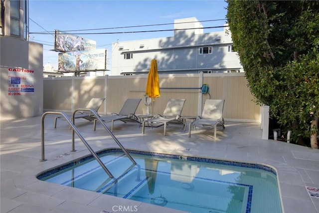 view of swimming pool with a patio, fence, and a community hot tub