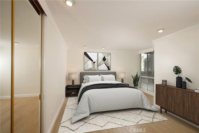 bedroom with ornamental molding, light wood-type flooring, and baseboards