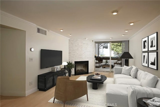 living room featuring a fireplace, crown molding, visible vents, light wood-style flooring, and baseboards