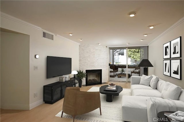 living area with a fireplace, light wood-style flooring, visible vents, and crown molding