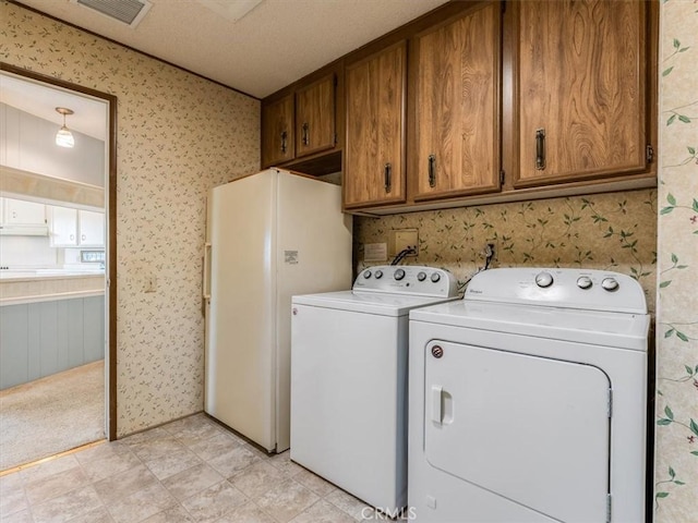 laundry room with cabinet space, visible vents, washer and clothes dryer, and a textured ceiling