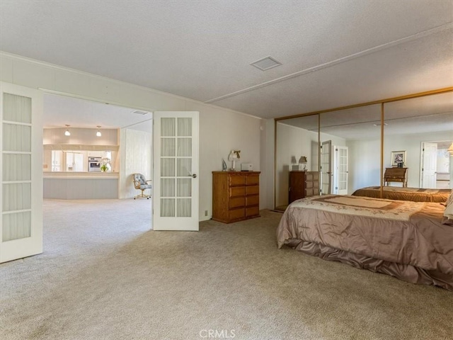 carpeted bedroom with a textured ceiling, french doors, a closet, and ornamental molding