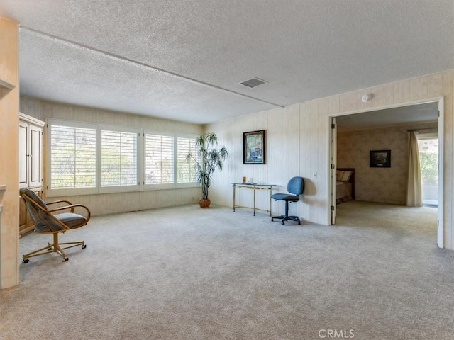 sitting room featuring carpet floors, visible vents, and a textured ceiling