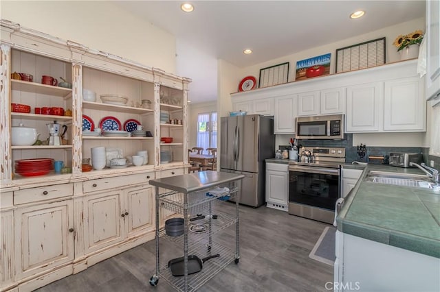 kitchen featuring stainless steel appliances, dark wood-type flooring, a sink, and white cabinetry