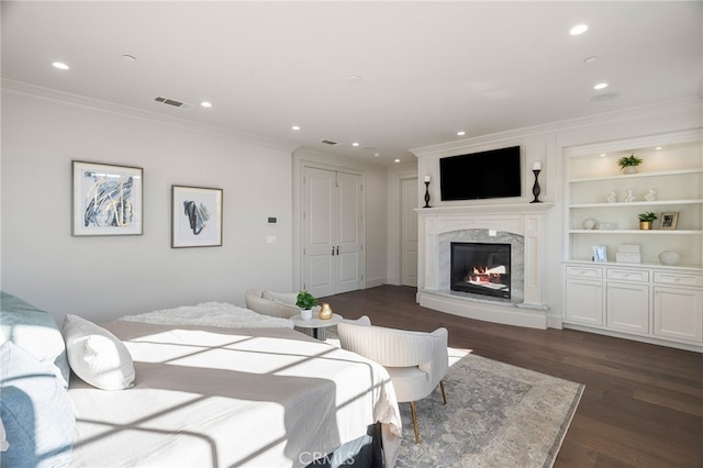 bedroom featuring ornamental molding, a high end fireplace, visible vents, and dark wood finished floors