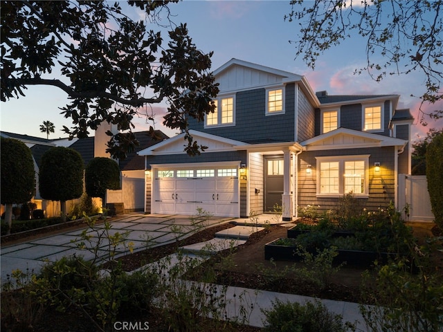 view of front of house featuring board and batten siding, driveway, a garage, and fence