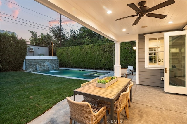 patio terrace at dusk with ceiling fan, outdoor dining area, a fenced in pool, and a yard