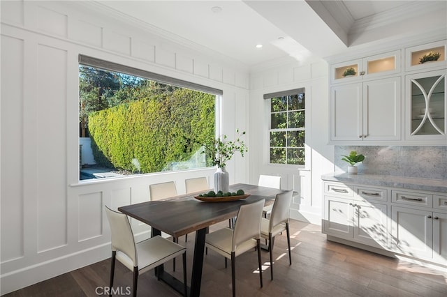 dining space featuring crown molding, dark wood-style flooring, recessed lighting, and a decorative wall