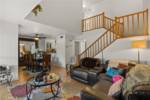 living room with stairs, ceiling fan, wood finished floors, and visible vents