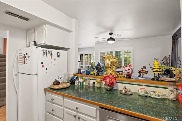 kitchen with a ceiling fan, visible vents, white cabinetry, freestanding refrigerator, and dark countertops