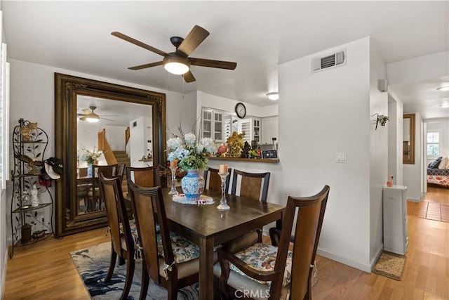 dining space with light wood-type flooring, baseboards, visible vents, and ceiling fan